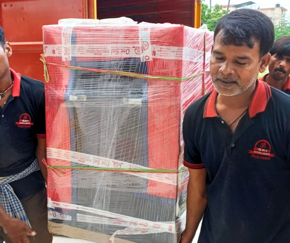 "Professional staff from Om Sai Packers and Movers carefully handling a wrapped and packed household item for safe relocation."